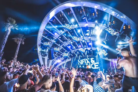 An outdoor crowd beneath an illuminated arched stage